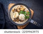 Small photo of Modern style traditional German cooked porcini mushroom soup with pretzel dumpling and fried potato chips offered as top view in a wrought-iron pan