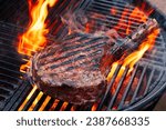 Small photo of Barbecue dry aged wagyu tomahawk steak offered as close-up on a charcoal grill with fire and smoke