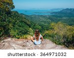 Girl on the view point of the mountain, sitting back to the camera, concept of freedom and traveling. Traveler enjoying the landscape from mountain in Tab Kak Hang Nak Nature Trail, Krabi, Thailand