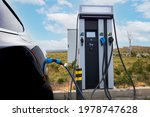 EV car plugged in charger and EV Charger station. Electric car charger station near the highway. Electric car. Zero emission car charging. Carbon free