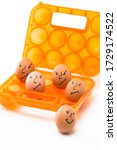 Small photo of Picture of Obsolete Orange Egg Hiolder. Placed With Eggs Symbolizing Embittered Human Faces.Against White Background. Vertical Image