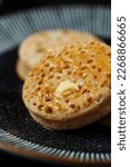 Small photo of Toasted english crumpet with butter on a black plate