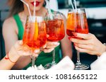 Woman hands toasting with aperol spritz cocktails