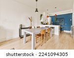 Small photo of a dining room with wood flooring and blue accent wall behind the table is an open kitchen area that has been used as a
