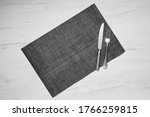 Top view of gray placemat table mat with knife and fork on white wooden table
