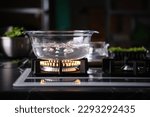 Small photo of Water boiling in transparent glass pot on gas stove
