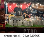 Small photo of Terengganu. February 11, 2024. Two workers in black prepare customer orders at a food stall. Location during the Food Mania festival in Kuala Terengganu. Night view.