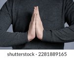 Small photo of Hands in prayer gesture close-up, hands in gray sweater. Sign of entreaty, reconciliation.
