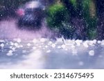 Small photo of Heavy rain with hail hits the roof of the car. Splashes and fragments of ice are blurred in motion. The concept of climate change. Driving on rainy days. Selective focus.