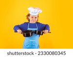 Small photo of Kid chef cook with cooking pot stockpot. Kid in cooker uniform and chef hat preparing food on studio color background. Cooking, culinary and kids food concept.