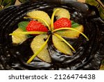 Small photo of black sapote dessert, black sapote candy with orange juice served on a ceramic plate garnished with orange segments and strawberries