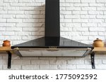 Black cooking hood with buttons and light against copy space on white brick wall. Kitchen appliance in apartment with modern interior