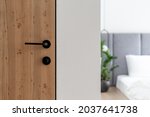 Closeup at door design, open room interior. Minimalist house style with doorknob, handle at wooden door. Entrance to modern bedroom, nobody at scandinavian apartment.