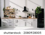 Modern kitchen interior with white furniture, appliances, decor and black refrigerator. Bright and spacious Dining room. Luxury apartment design project 