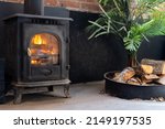 Close up view of firewood near black metal fire place in cozy living room. Concept of heating the house in winter season. Modern and energy efficient fireplace indoors apartment
