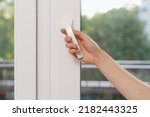 Small photo of Cropped view of woman hand open plastic window in living room. Female hold handle, closed double glazed pvc balcony door, protect bedroom and insulate apartment from outdoors noise