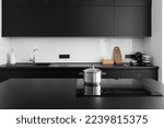 stainless steel saucepan with lid on induction stove on island countertop, contemporary cupboard, sink, water tap and kitchenware at stylish kitchen