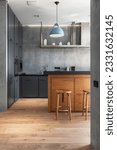 Small photo of Vertical shot of elegant kitchen with gray cabinet, wooden table and chairs on parquet. Stylish interior design in modern apartment. Tidy, neat storage concept