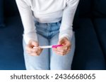 Small photo of Woman checking at result on confirmed pregnancy test, making hard decision about abortion unwanted or unplanned child. Concept of birth control, reproductive health