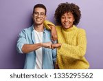 Small photo of Young diverse couple give fist bump, agree to bring plan to life, smile broadly, have mixed race relationships, have good friendly partners, isolated over purple wall. I agree with you concept