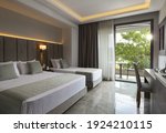 Modern apartment interior of family hotel room with grey oak wood furniture, single, double king size bed. Contemporary bedroom with open big window, green garden sunset view door