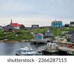 Small photo of Peggy's Cove, NS, CAN, August 15, 2023 - A view of the houses on a hill along the water at Peggy's Cove, Nova Scotia with boats docked at the wharf beneath them.