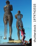 Small photo of Batumi, Adjara, Georgia, 05-02-2021: girl look at Ali and Nino, dynamic sculpture on the embankment, sculptor Tamara Kvesitadze