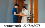 Small photo of Young Asian delivery man in blue navy uniform knock door home delivery online shopping box to woman customer in front door and woman sign name accept on smartphone at house. home delivery concept.