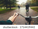 First-person view of cyclist. Group of friends riding bicycles in rainy autumn park. Rider's hand in on a bicycle handlebar. Healthy lifestyle