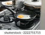 egg frying on a black frying pan on top of a gas stove burner. colombian cooking.