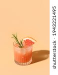 Small photo of Grapefruit juice garnish rosemary sprig on color beige background. Mocktail Paloma. Close up. Vertical format.