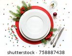 Christmas table setting with vintage dishware, silverware and red decorations on white background. Top view.  