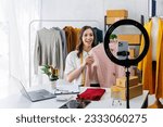 Small photo of Beautiful woman describe selling clothes on camera live broadcast on social network at home, Online selling clothes on social media. Vlogger woman influencer, SME retail store owner.