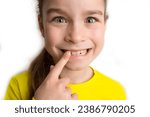 Little girl stands on a white background with a beautiful smile, children crooked teeth, pediatric dentistry. Crooked teeth close-up. Correction of malocclusion is required. 
