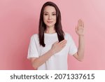 Small photo of Photo of young girl hand on heart make oath promise to tell the truth isolated over pink color background