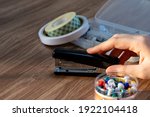 Close up shot of a woman touching a stapler with the background of other office equipments on a wooden table