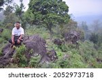 Small photo of The old asceted with his interludes sat on a rock. Mount Arjuna. Pasuruan, Indonesia, October 5, 2021
