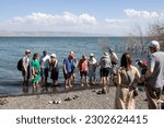 Small photo of Tabgha, Israel - December 28, 2017: People walking or seating on the coast of the lake near The Church of the Primacy of St. Peter.
