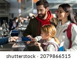 Small photo of Unrecognizable employee of airport checking passports and biometric data while working with family of passengers. Happy parents and their daughter having trip