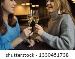Smiling girls holding glasses of prosecco and making cheers in cafe. Celebration  concept.