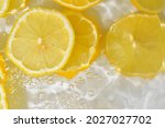 Slices of lemon in water on white background. Lemon close-up in liquid with bubbles. Slices of yellow ripe lemon in water. Macro image of fruits in water