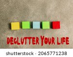 Small photo of Inspiration showing sign Declutter Your Life. Business approach To eliminate extraneous things or information in life Stack of Sample Cube Rectangular Boxes On Surface Polished With Multi-Colour