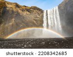 The mighty Skógafoss waterfall under a clear blue sky, with a beautiful double rainbow caused by its constant spray, near Route 1, Ring Road, Southern Region, Iceland