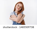 Small photo of Tender cheerful redhead girl with long ginger hair tightly hug herself express self-love and care smiling broadly, close eyes tilt head emrace own body and flaws, stand white background pleased