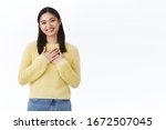 Cute humble and grateful asian girl thanking for congratulations, press hands to heart and smiling blushing from happiness and joy receiving gifts, looking touched, standing against white background
