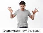 Portrait of excited man raise hands and look amazed down, found something on floor, standing happy against white background