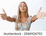 Small photo of Glamour blond girl pucker lips, kissing and stretching out hands for hug, reaching to you clingy, standing over white background