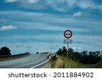 No overtaking sign. Road sign on the road in front of the bridge against the blue cloudy sky . High quality photo