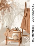 Small photo of Natural waffle linen towels in earth tones on wood bench and towel ladder with bamboo toothbrushes, rattan baskets, and soap dispenser. Daily body care, spa and wellness zero waste bathroom concept