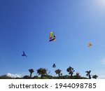 Small photo of Creatively designed kites lifting into the sky with the semblance of a dissipating rainbow in the background